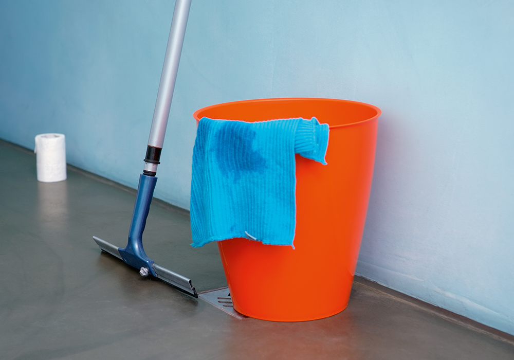 Cleaning bucket and scrubbing brush against the wall